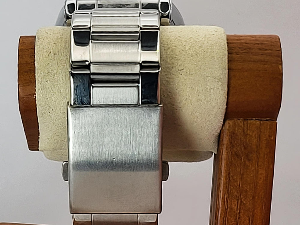 Close-up of a stainless steel Aokulasic Open Heart Automatic watch band clasp mounted on a cream-colored display stand with a wooden frame.