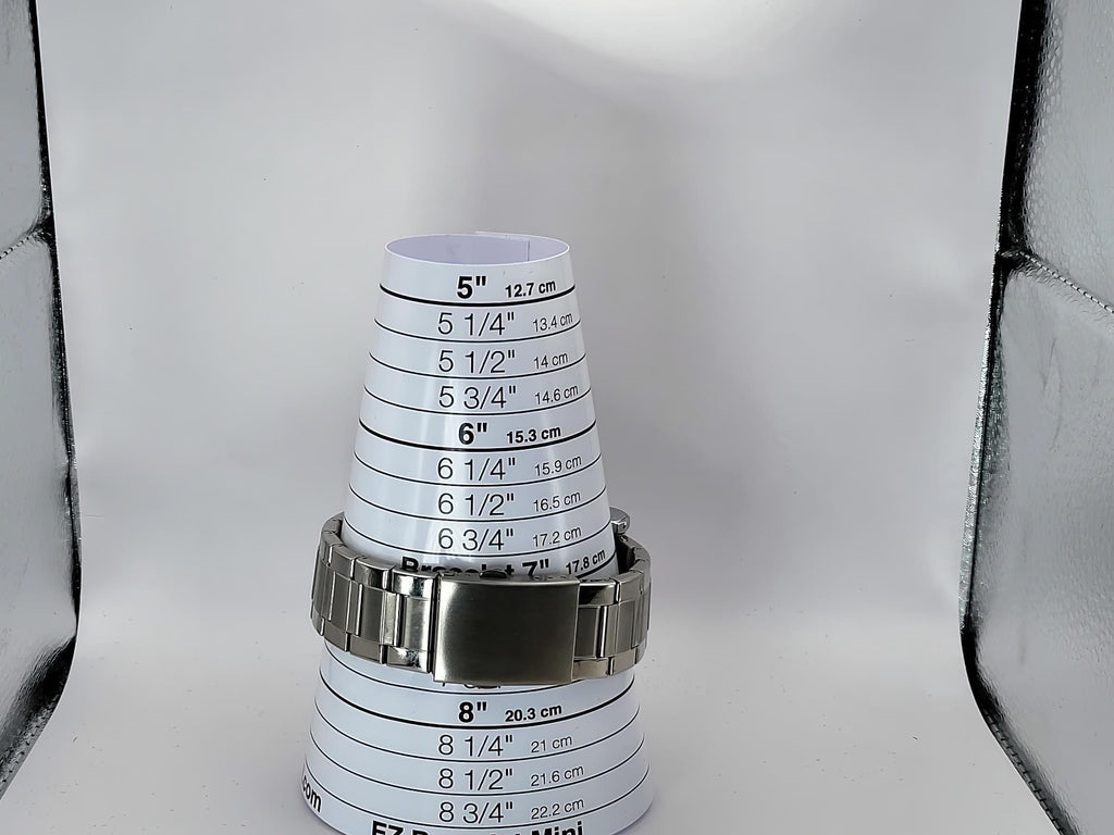 A silver metal link watch band for a Aokulasic Open Heart Automatic shown around a stack of white paper cone size guides printed with inch and centimeter measurements, on a light gray background.