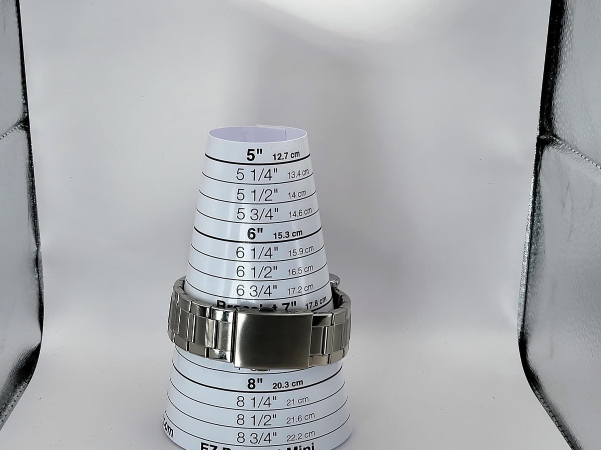 A silver metal link watch band for a Aokulasic Open Heart Automatic shown around a stack of white paper cone size guides printed with inch and centimeter measurements, on a light gray background.