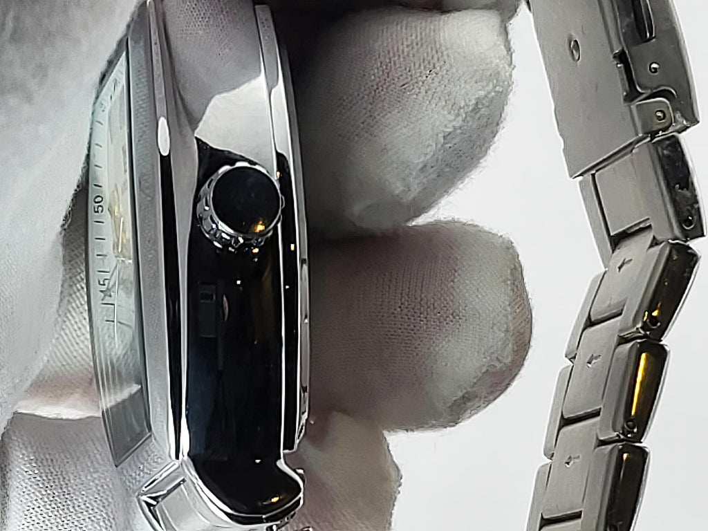 Close-up of a silver stainless stee Aokulasic Open Heart Automatic watch with a metal link bracelet, held by a hand wearing white gloves. The watch has a polished chrome case with a black bezel and a clear crystal.