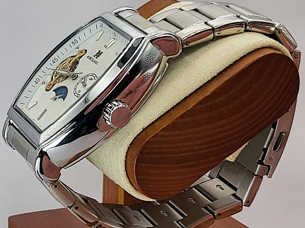 A silver-tone Aokulasic Open Heart Automatic stainless steel wristwatch with a white dial and skeletonized movement, displayed on a wooden stand with a cream cushion.