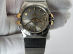 Omega Constellation wristwatch with a two-tone stainless steel and gold case, held in a white gloved hand.