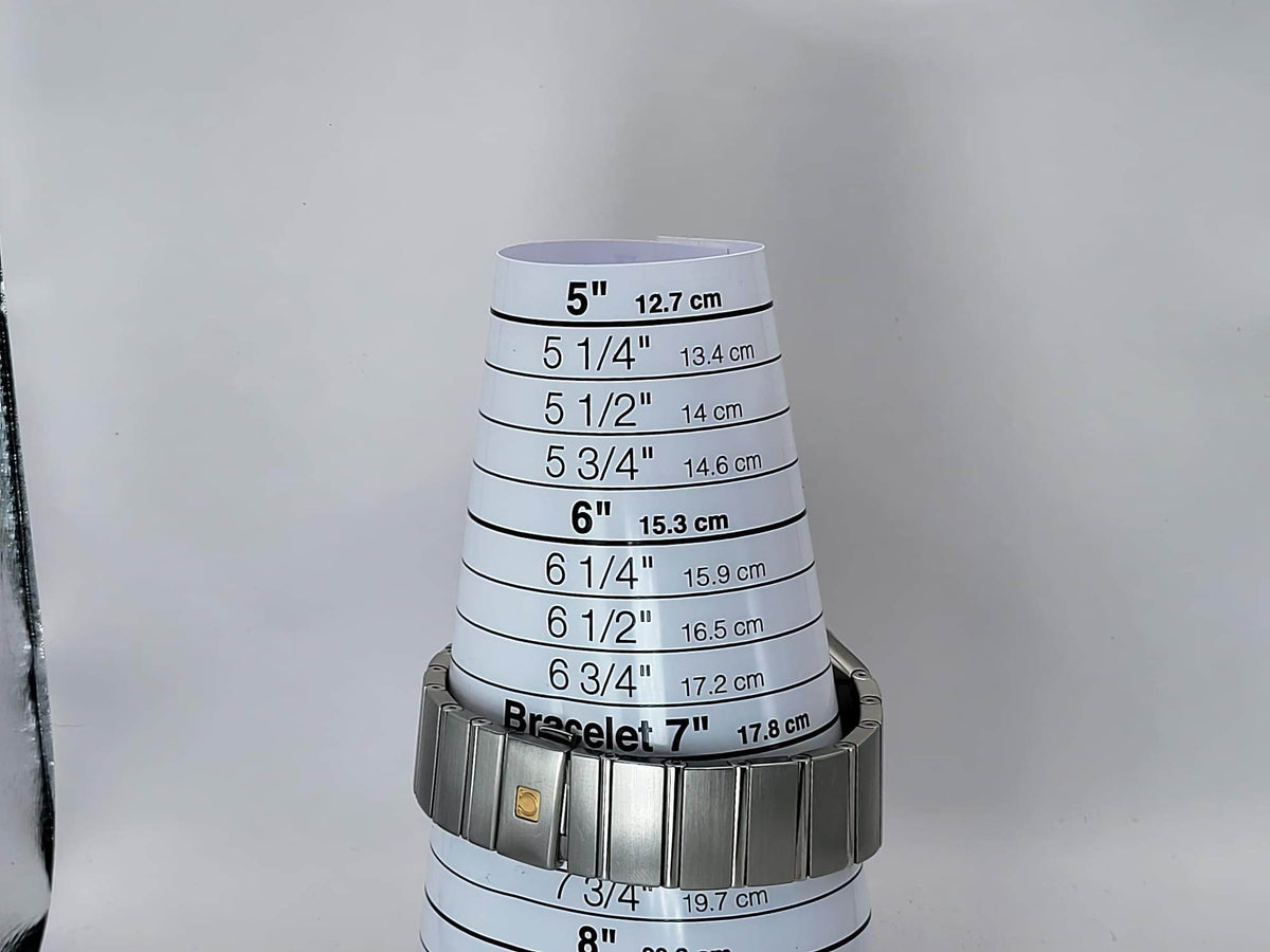 A silver metal bracelet watch wristband for a Omega Constellation watch, shown wrapped around a white cone-shaped size gauge printed with bracelet measurements in inches and centimeters.