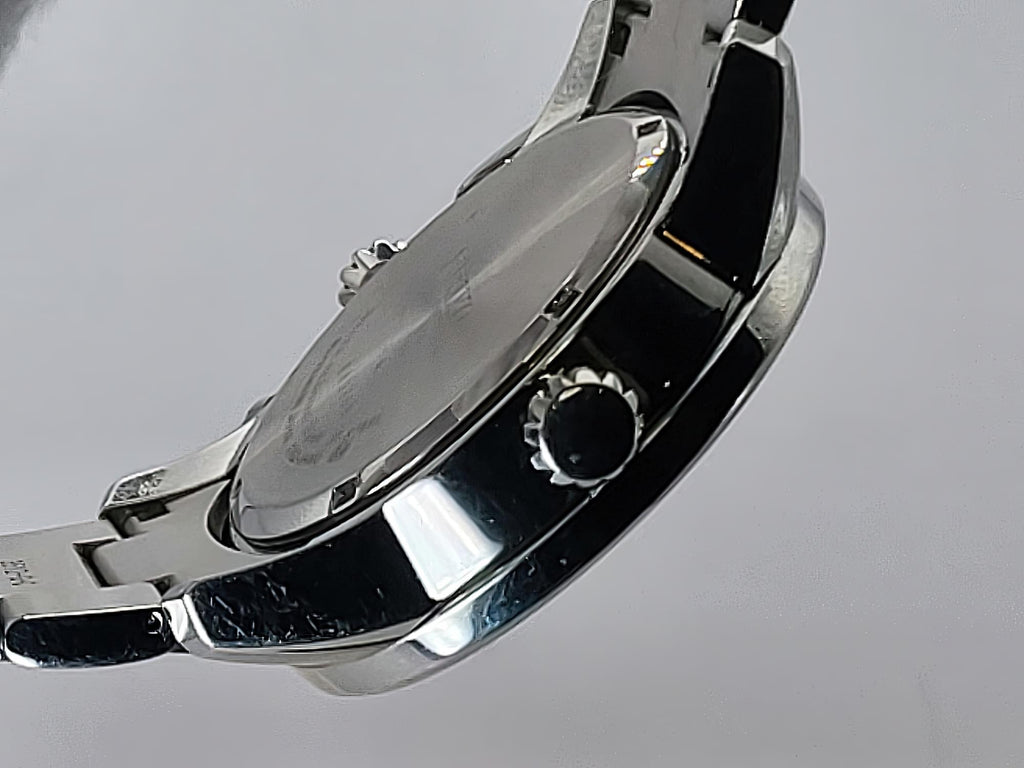 Close-up of the side and back of a stainless steel Seiko Flightmaster wristwatch with a polished metal case and link bracelet on a light gray background.