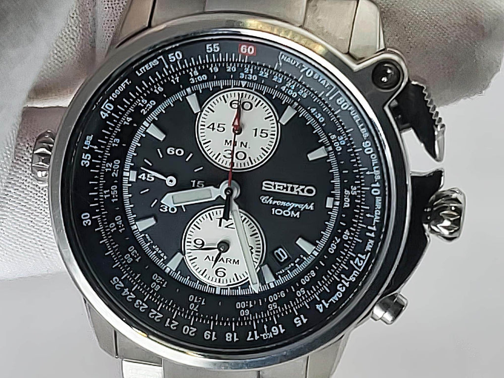 A Seiko Flightmaster chronograph wristwatch with a black dial, silver-tone stainless steel case, and white subdials, photographed close-up against a light gray background.
