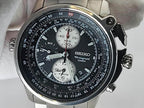 A Seiko Flightmaster chronograph wristwatch with a black dial, silver-tone stainless steel case, and white subdials, photographed close-up against a light gray background.