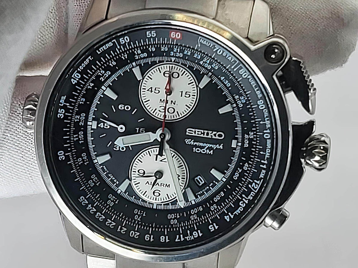A Seiko Flightmaster chronograph wristwatch with a black dial, silver-tone stainless steel case, and white subdials, photographed close-up against a light gray background.
