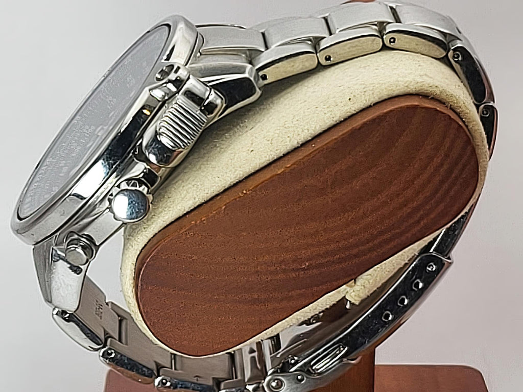 Silver stainless steel Seiko Flightmaster watch with a matching metal link bracelet, displayed on a cushion with a wood-grain insert against a light gray background.