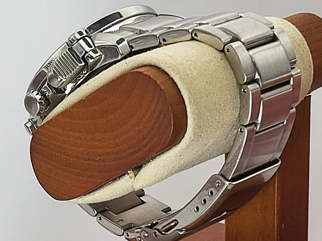 A silver stainless steel Seiko Flightmaster watch with a metal link bracelet, shown from the side on a beige foam display stand with a wooden backing.