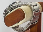 A silver stainless steel Seiko Flightmaster watch with a metal link bracelet, shown from the side on a beige foam display stand with a wooden backing.