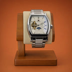 A luxury silver-toned Aokulasic Open Heart Automatic wristwatch with a white dial and skeletonized movement, displayed on a wooden watch stand against a solid orange background.