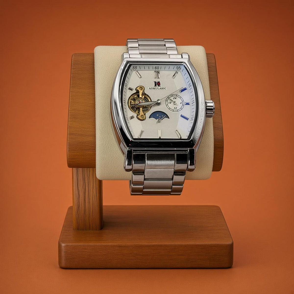 A luxury silver-toned Aokulasic Open Heart Automatic wristwatch with a white dial and skeletonized movement, displayed on a wooden watch stand against a solid orange background.