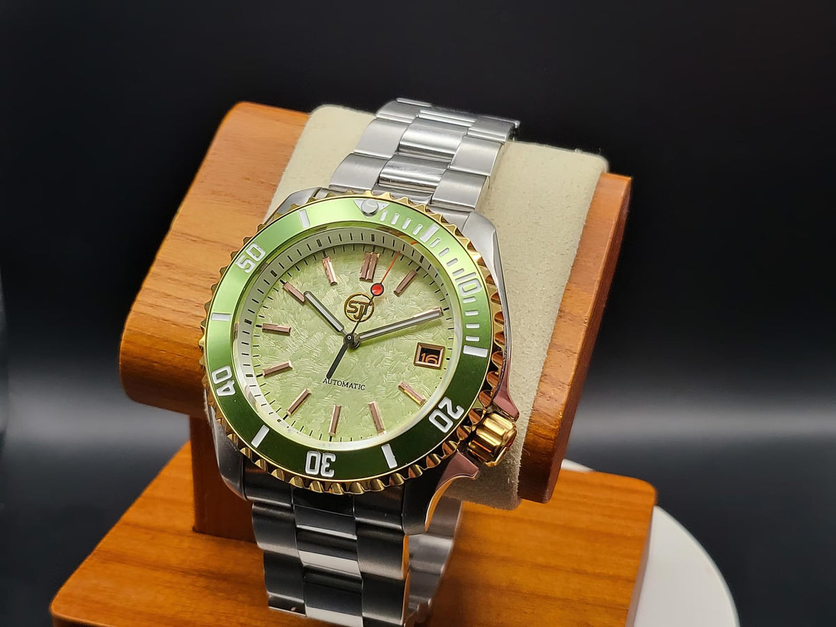 The Coconut SJT Original wristwatch with a green dial and green bezel, displayed on a wooden stand against a dark background.