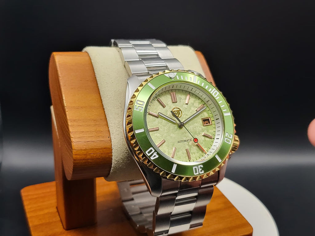 The Coconut SJT Original wristwatch with a green bezel and light green dial, displayed on a wooden stand against a dark background.