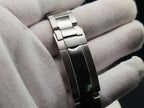 A close-up of a polished stainless steel link bracelet for The Memo SJT Original wristwatch held in a white-gloved hand against a dark background.