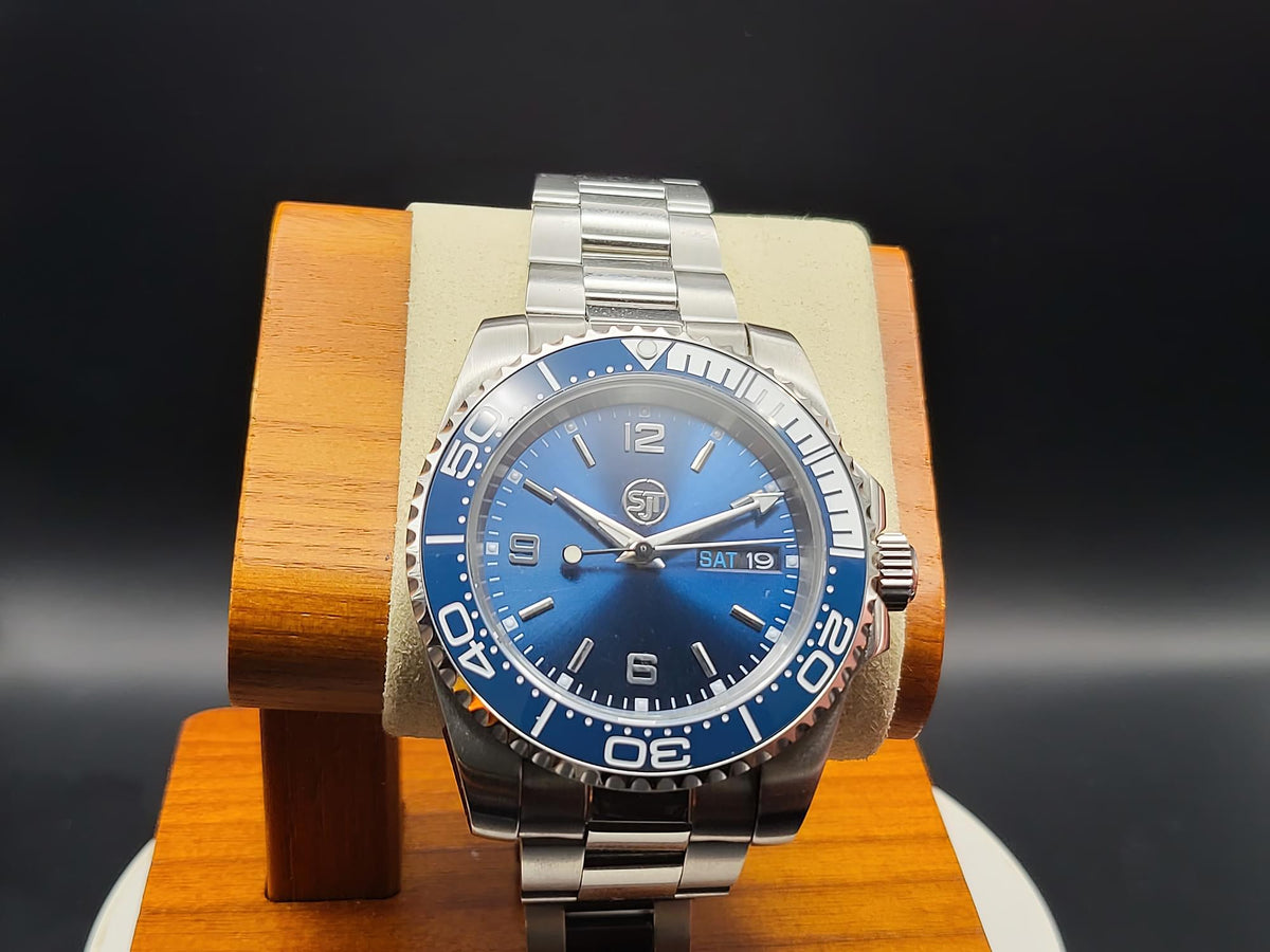 The Memo SJT Original wristwatch with a blue dial and blue bezel, displayed on a wooden stand against a dark background.