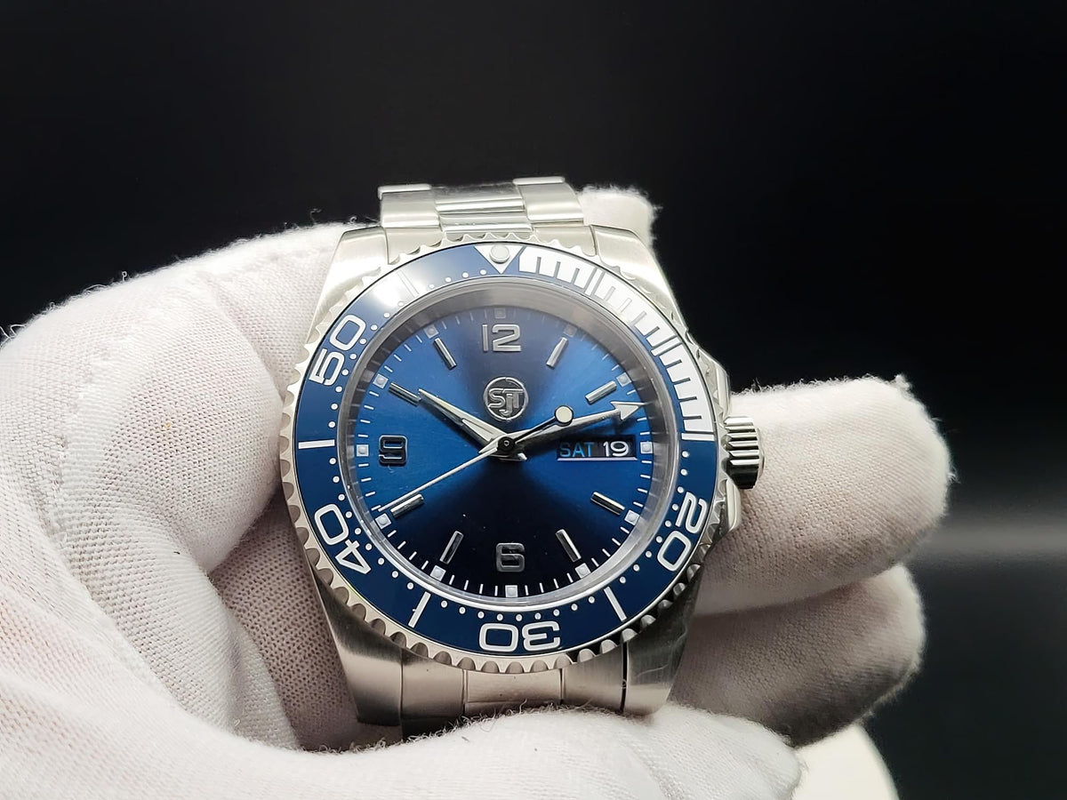 The Memo SJT Original wristwatch with a blue dial and blue bezel, held in a white gloved hand against a dark background.