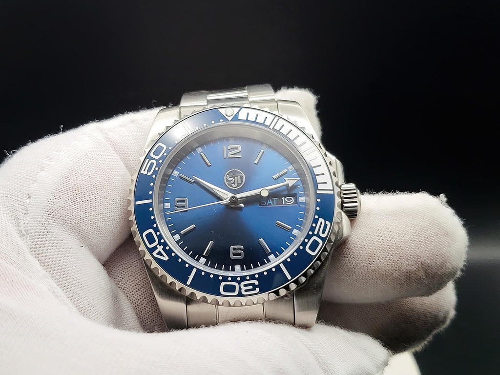 The Memo SJT Original wristwatch with a blue dial and blue bezel, held in a white-gloved hand against a dark background.
