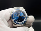 The Memo SJT Original wristwatch with a blue dial and blue rotating bezel, held in a white gloved hand against a dark background.