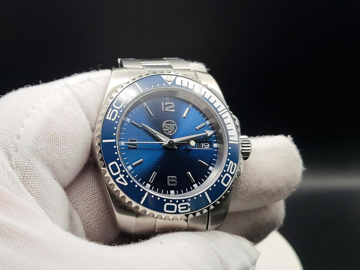 The Memo SJT Original wristwatch with a blue dial and blue rotating bezel, held in a white gloved hand against a dark background.