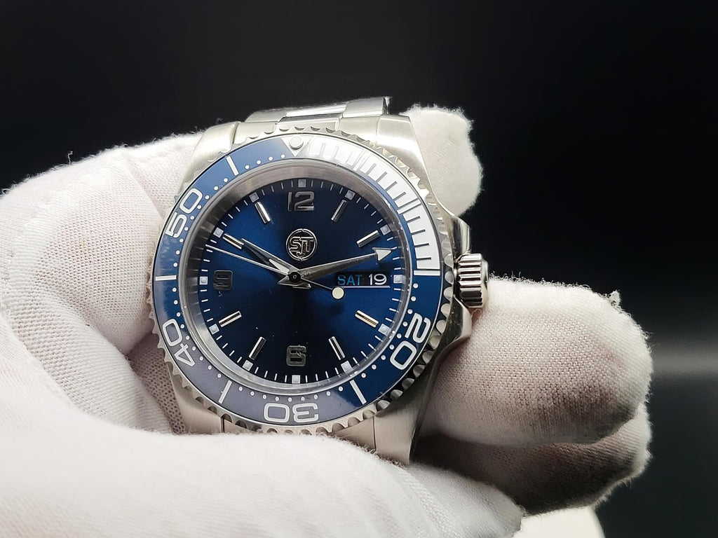 The Memo SJT Original wristwatch with a blue dial and blue bezel, held in a white gloved hand against a dark background.