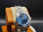 The Memo SJT Original wristwatch with a blue dial and blue bezel, displayed on a wooden stand against a dark background.