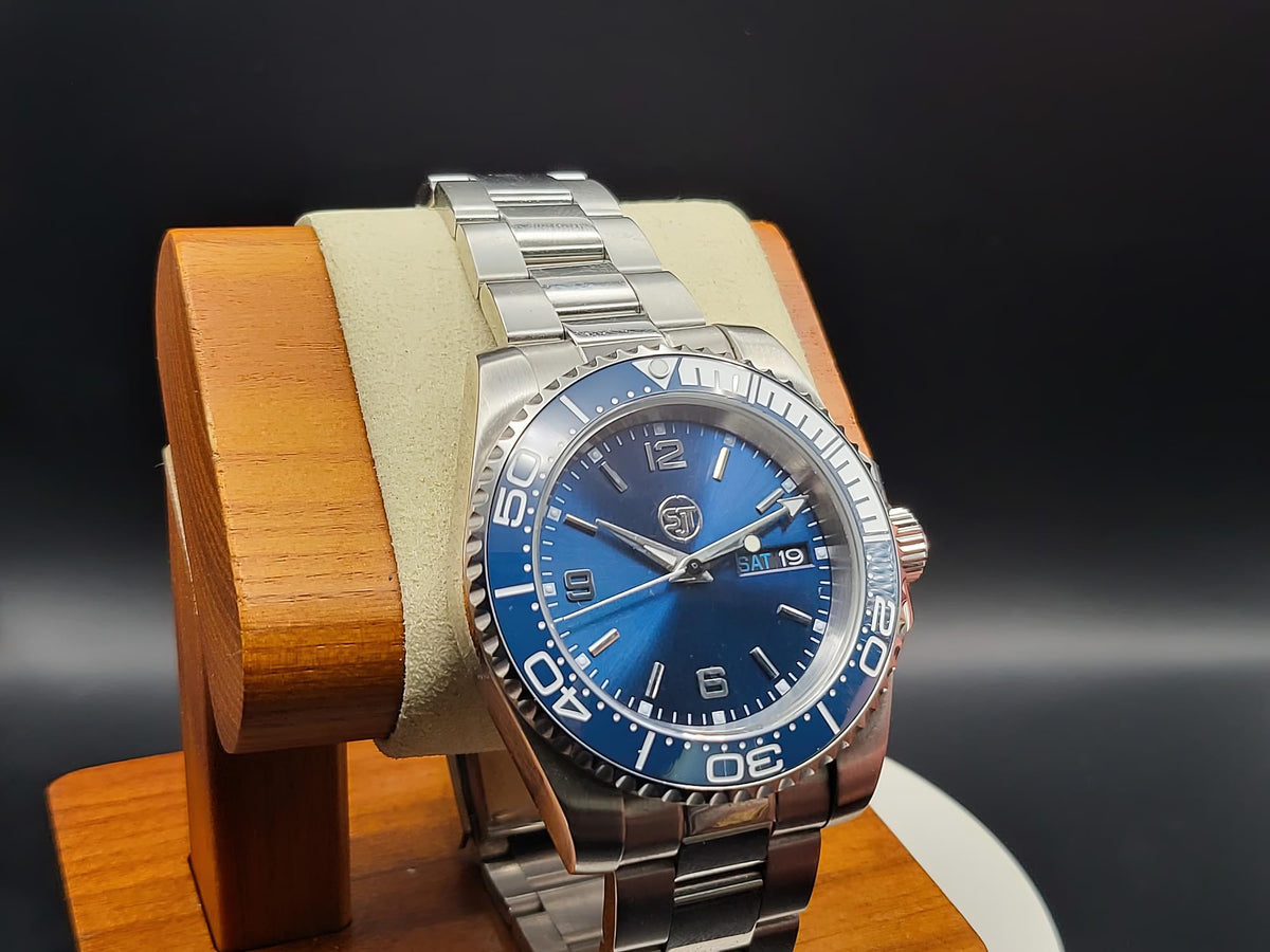 The Memo SJT Original wristwatch with a blue dial and blue bezel, displayed on a wooden stand against a dark background.