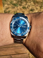 The Memo SJT Original wristwatch with a blue dial and blue bezel, worn on a person's wrist against a blurred outdoor background.