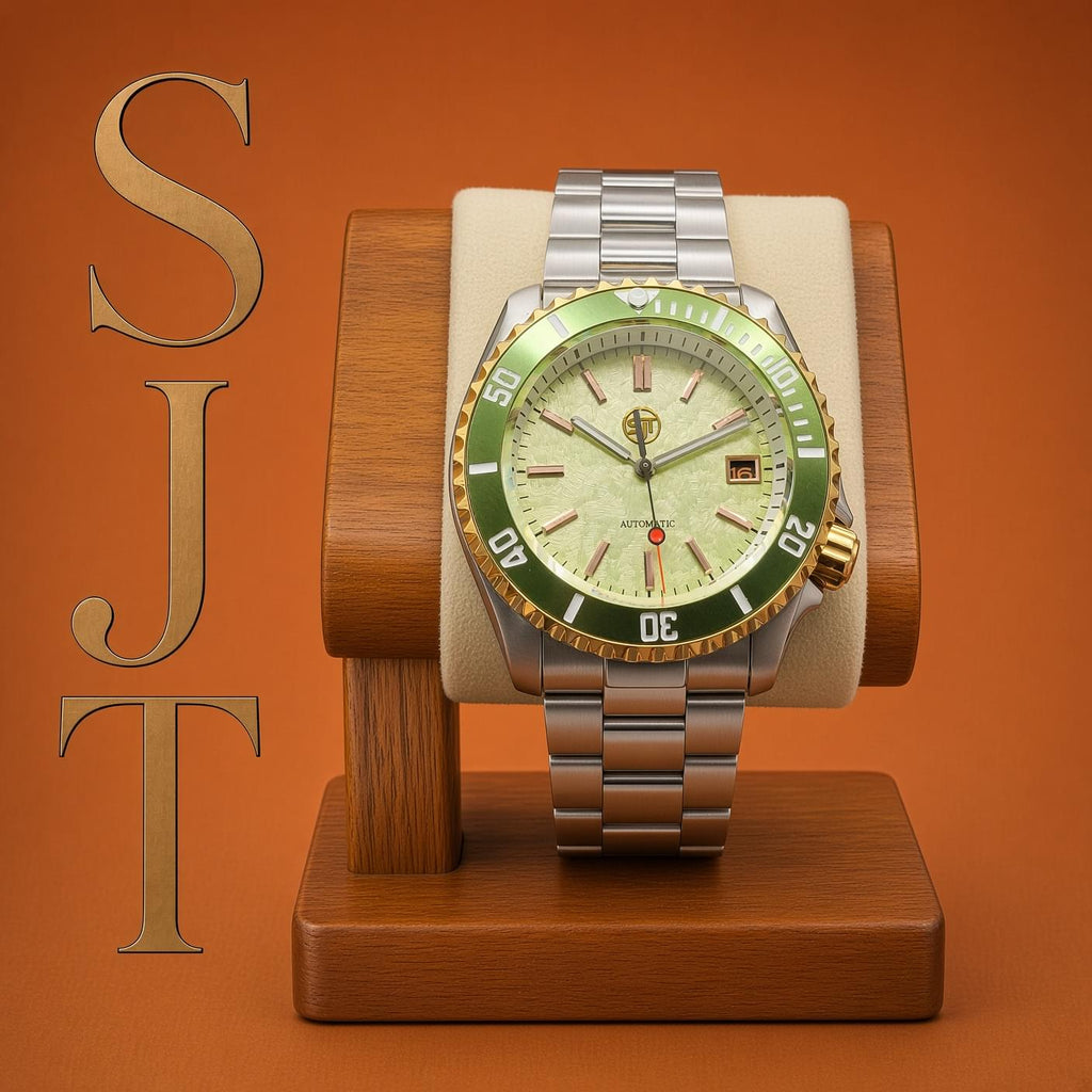 The Coconut SJT Original wristwatch with a green and gold bezel, cream dial, and silver-tone metal bracelet, displayed on a wooden watch stand against a warm orange background. The letters 'SJT' are vertically written on the left side.