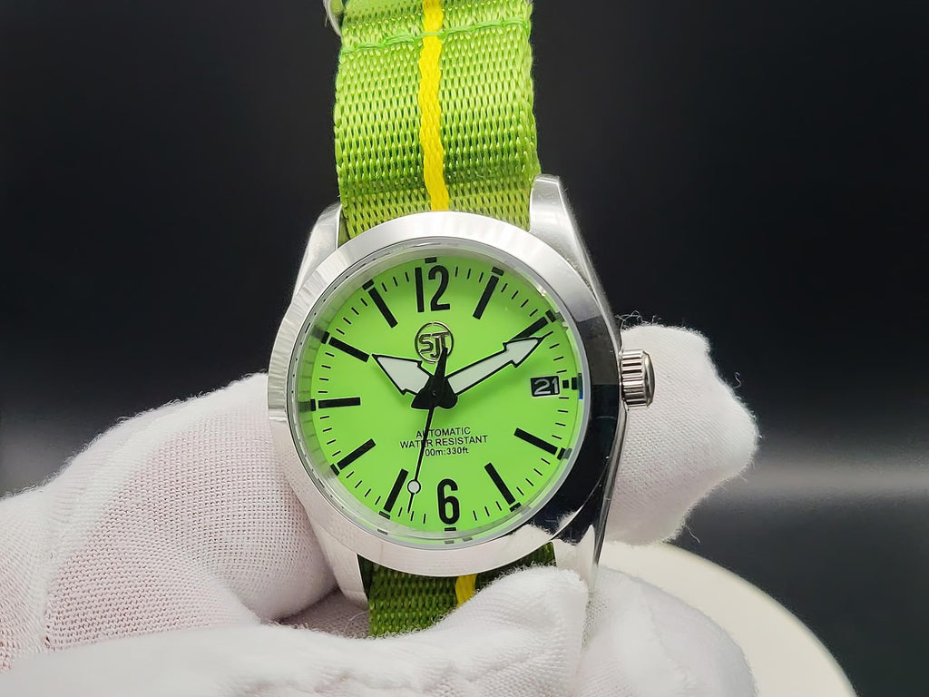 The P-A-R-T-Y? SJT Original wristwatch with a bright green dial and a green fabric strap featuring a yellow stripe, held by a white gloved hand against a dark background.