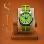 The P-A-R-T-Y? SJT Original wristwatch with a bright green dial and green fabric strap featuring a yellow stripe, displayed on a wooden stand against an orange background. Large stylized letters 'SJT' appear vertically on the left.