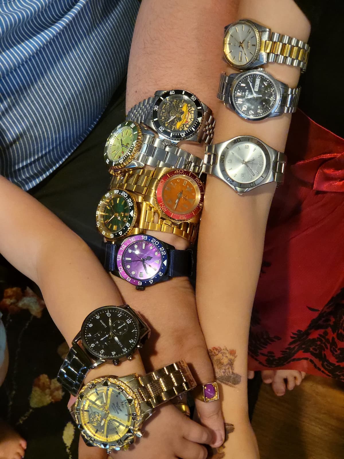 A collection of multiple wristwatches with different dials, straps, and bezels displayed on several people's arms in a crowded, casual setting.